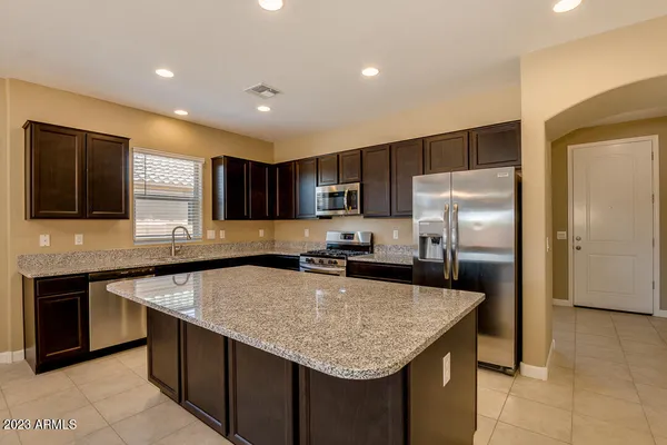 a kitchen with kitchen island granite countertop a sink and a refrigerator