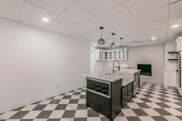 a living room with stainless steel appliances kitchen island granite countertop a sink and a black white cabinets