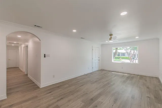 an empty room with wooden floor and windows