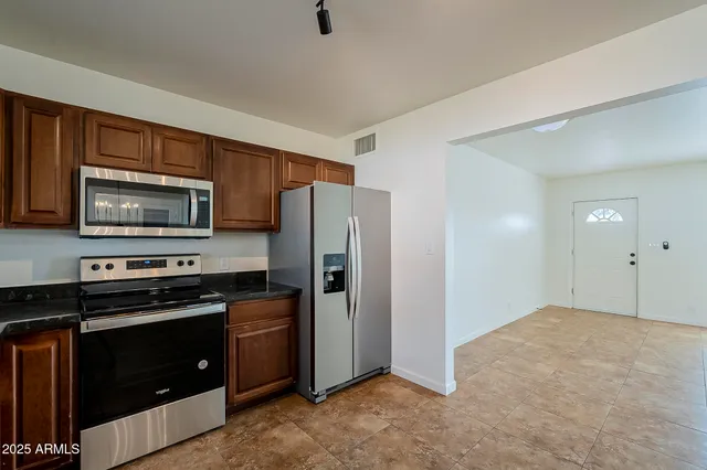 a kitchen with stainless steel appliances granite countertop a refrigerator and a stove top oven