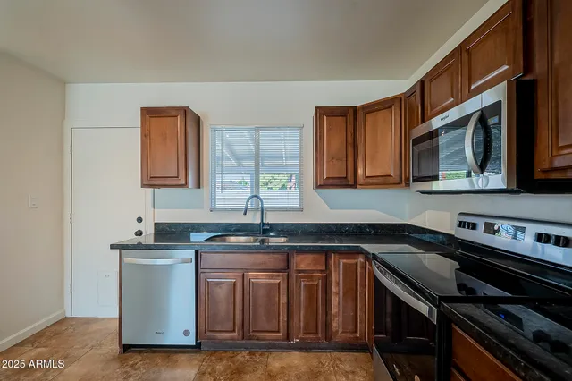 a kitchen with granite countertop a sink a stove and cabinets