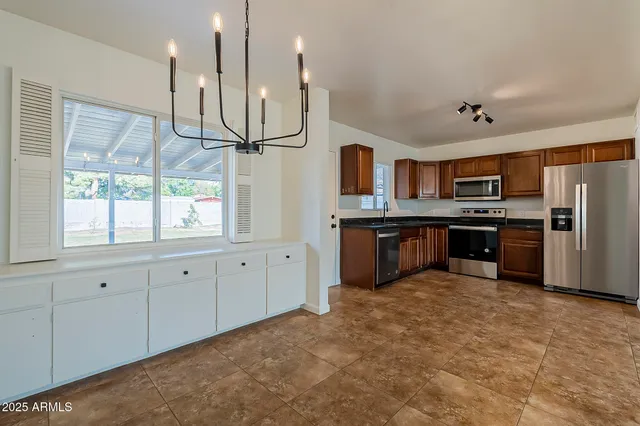 a kitchen with stainless steel appliances granite countertop a refrigerator a sink a stove and oven with wooden floor