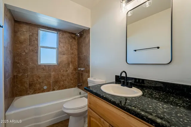 a bathroom with a granite countertop sink a toilet a mirror and bathtub