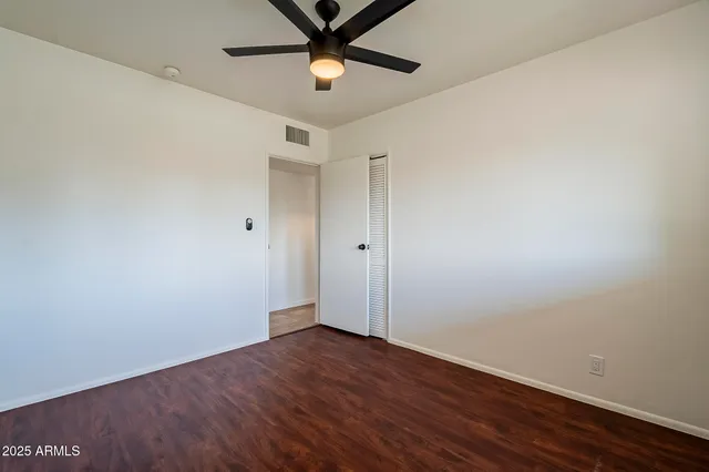 an empty room with wooden floor and ceiling fan
