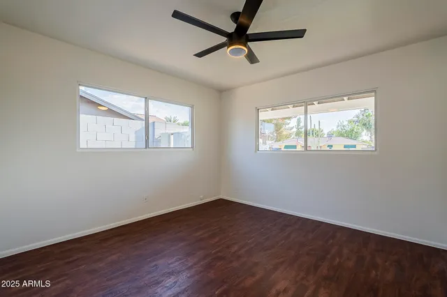 a view of empty room with wooden floor and fan