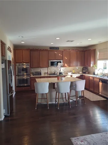 a kitchen with stainless steel appliances a table chairs refrigerator and a sink