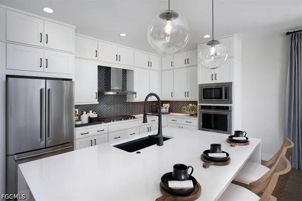 a kitchen with stainless steel appliances kitchen island granite countertop a stove a refrigerator a sink a stove and white cabinets