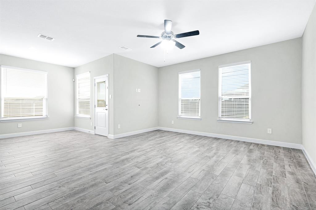 15501 Balham Path Fort Worth, TX 76247 - Photo 6 of 22 an empty room with wooden floor ceiling fan and windows