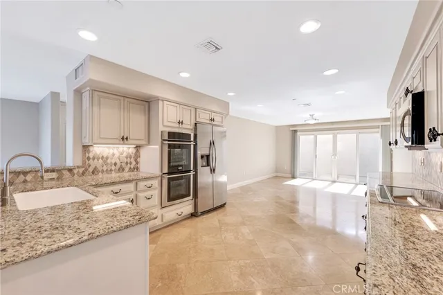 a large kitchen with granite countertop a large counter top stainless steel appliances a sink and cabinets