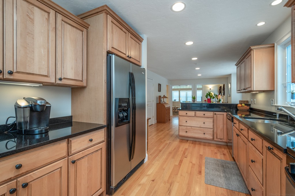 1094 Hill Road, Unit 1094 Boxborough, MA 01719 - Photo 8 of 38 a kitchen with stainless steel appliances granite countertop a refrigerator a sink dishwasher a stove and white countertops with wooden floor