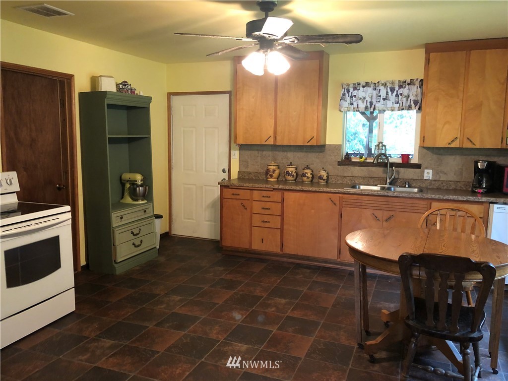 17706 Butler Road Snohomish, WA 98290 - Photo 7 of 22 a kitchen with stainless steel appliances granite countertop a sink a stove a table and chairs in it