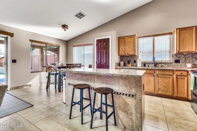 a kitchen with stainless steel appliances granite countertop table chairs sink and cabinets