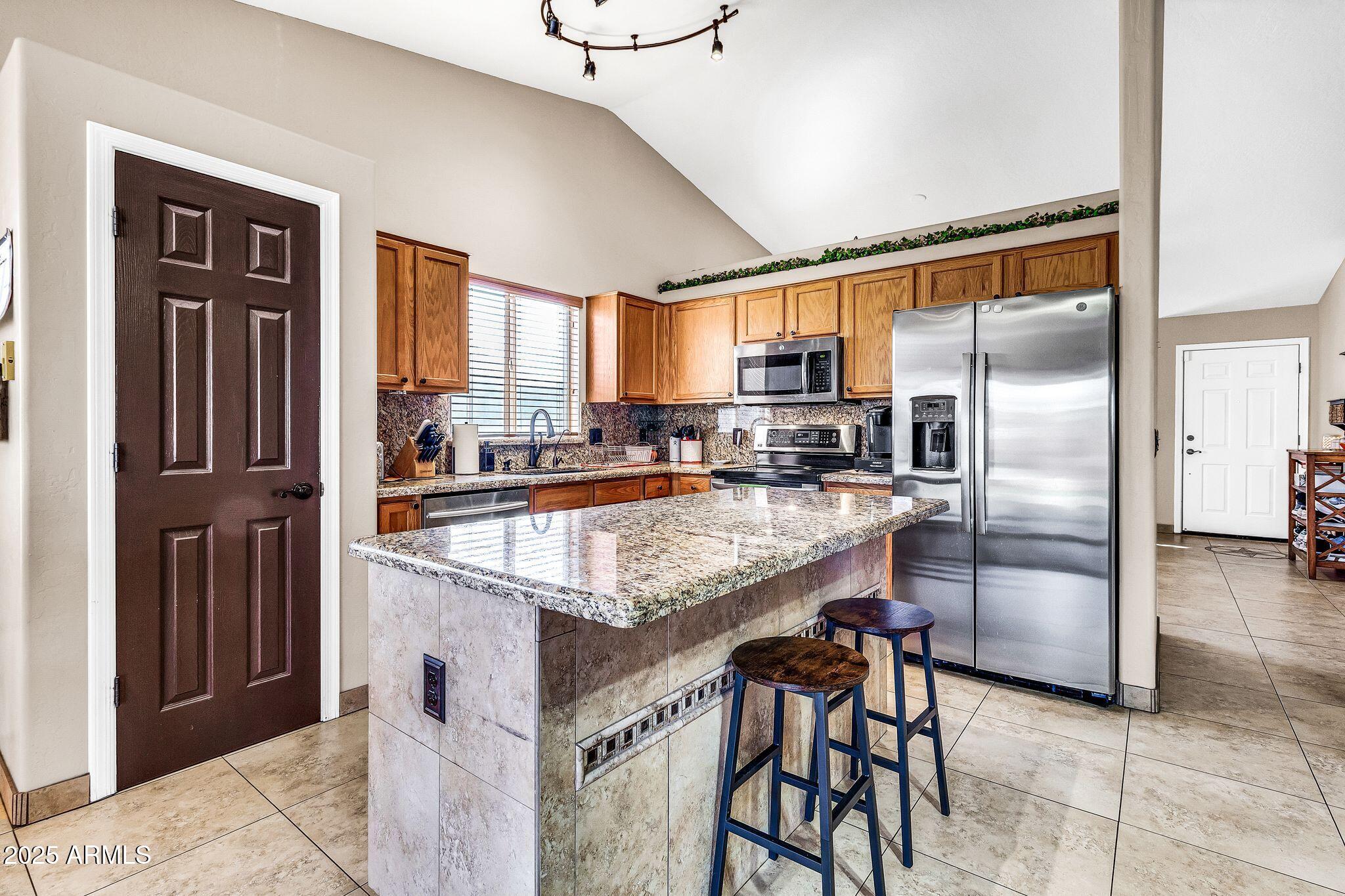 3048 East Erie Street Gilbert, AZ 85295 - Photo 11 of 44 a kitchen with kitchen island a counter top space cabinets and stainless steel appliances