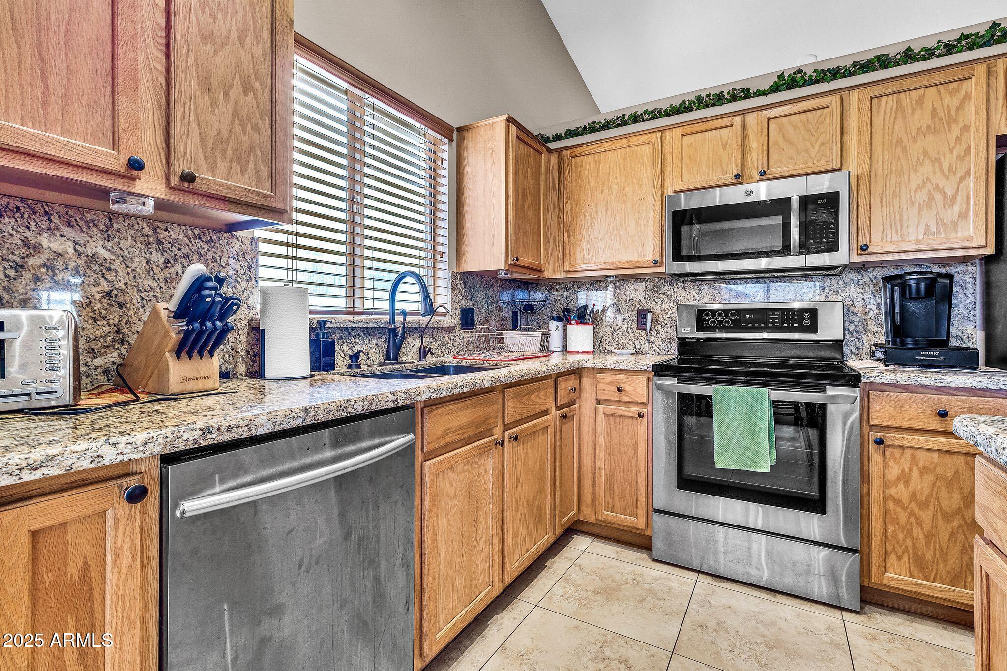 3048 East Erie Street Gilbert, AZ 85295 - Photo 13 of 44 a kitchen with stainless steel appliances granite countertop a sink stove and microwave