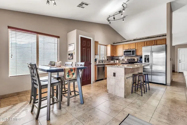 a dining area with stainless steel appliances kitchen island granite countertop a dining table chairs and granite counter tops