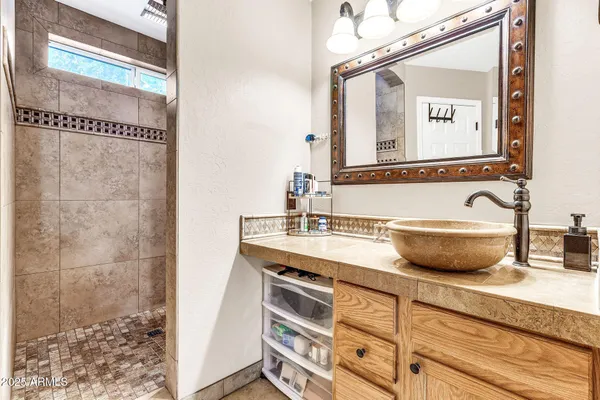 a bathroom with a granite countertop sink a mirror and shower