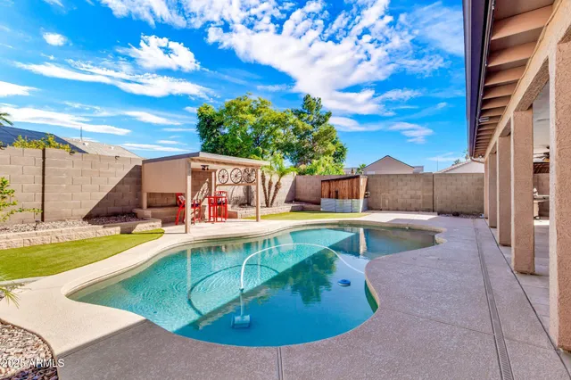 a view of a swimming pool with a patio and a yard