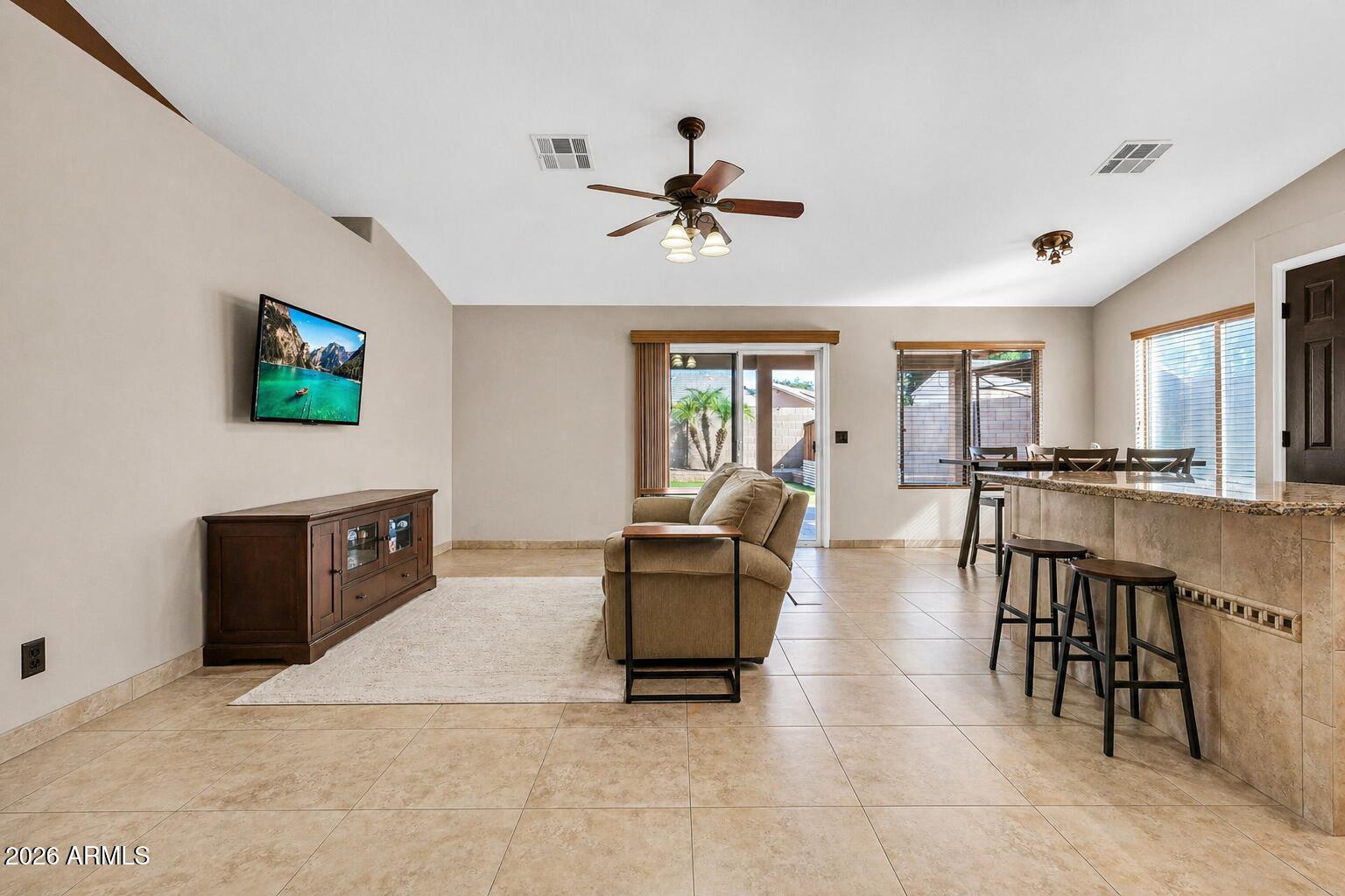 3048 East Erie Street Gilbert, AZ 85295 - Photo 7 of 41 a living room with furniture a dining table and a flat screen tv