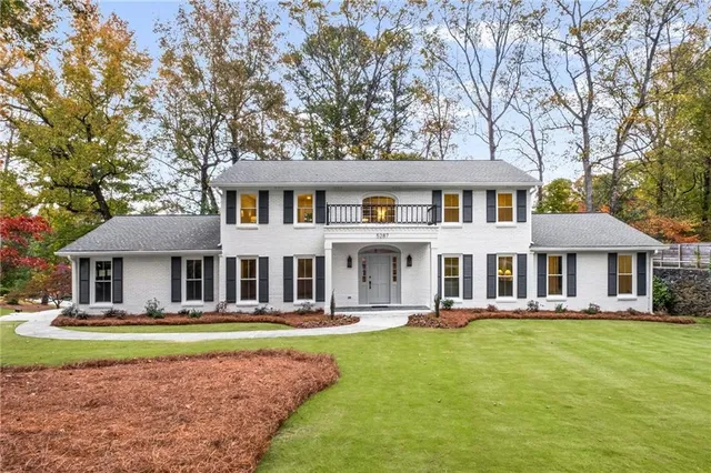 a front view of a house with garden and trees