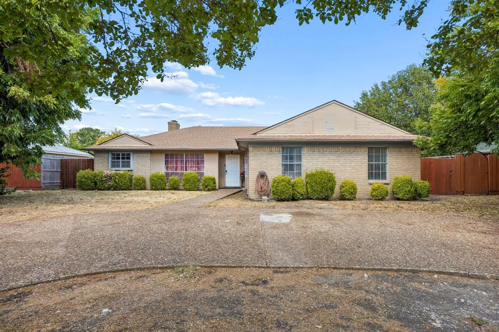 1701 East Spring Valley Road Richardson, TX 75081 - Photo 1 of 28 Brick exterior, pitched roofline, mature trees, gravel driveway, and a detached shed