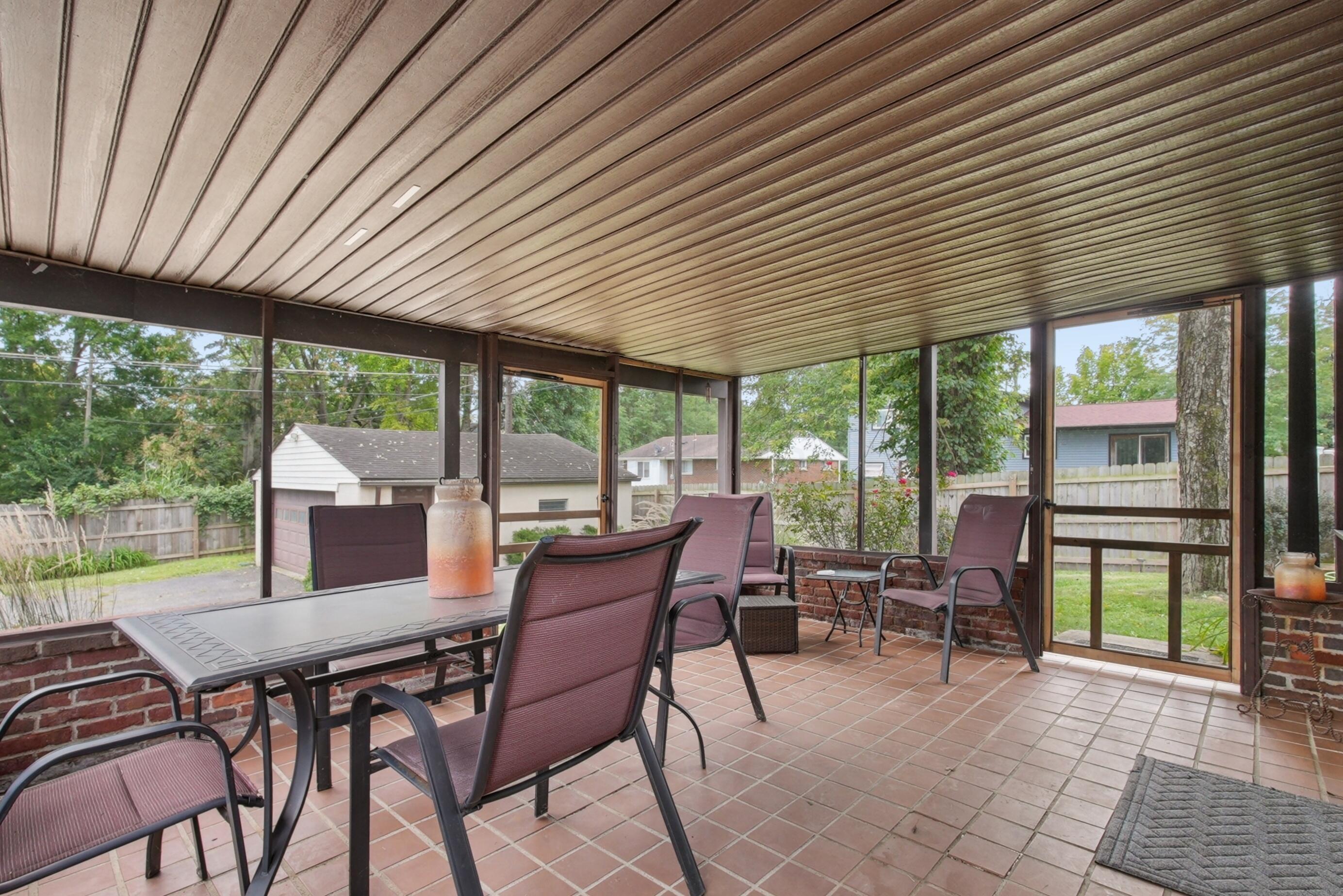 1636 Courtright Road Columbus, OH 43227 - Photo 13 of 35 Large screened-in porch featuring a full brick knee wall, tiled flooring, slatted ceiling, and multiple screened panels