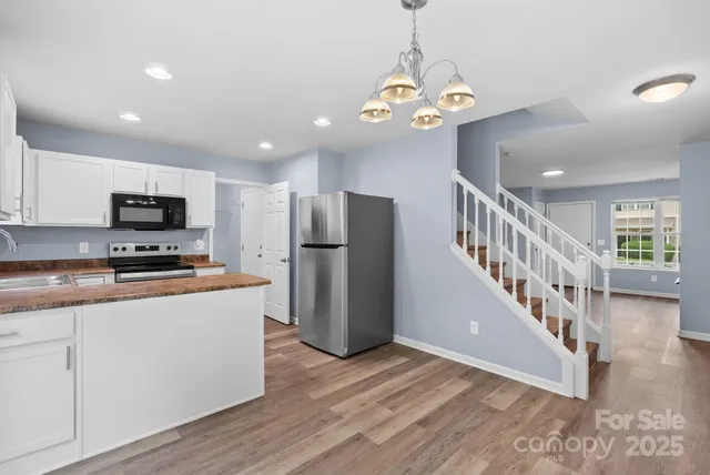 a view of a kitchen with stainless steel appliances granite countertop a refrigerator a stove a microwave oven a sink with island and wooden floor