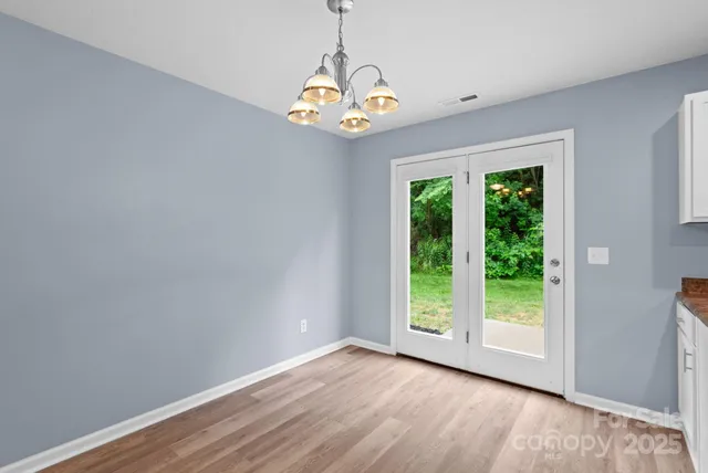 a view of an empty room with window and wooden floor