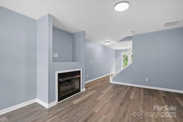 a view of empty room with wooden floor and fireplace