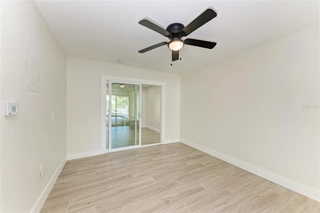 an empty room with wooden floor fan and windows