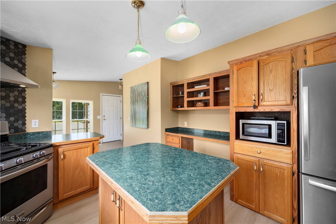 294 Twp 150 Road Sullivan, OH 44880 - Photo 12 of 39 Spacious kitchen featuring a central island with a multi-sided countertop, light wood cabinetry, stainless steel appliances, and a dark hexagonal tile backsplash
