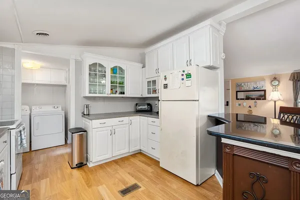 a kitchen with a refrigerator a stove a sink and white cabinets with wooden floor