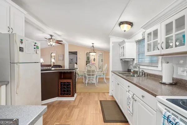 a kitchen with stainless steel appliances granite countertop a refrigerator a oven a sink and white cabinets with wooden floor