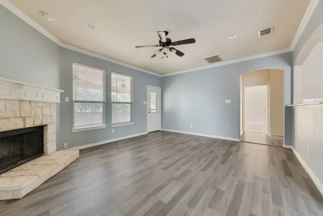 an empty room with wooden floor fireplace and windows