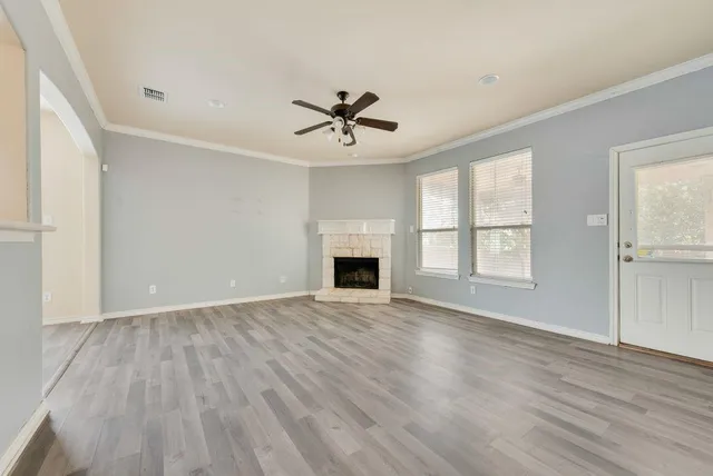 wooden floor fireplace and windows in an empty room