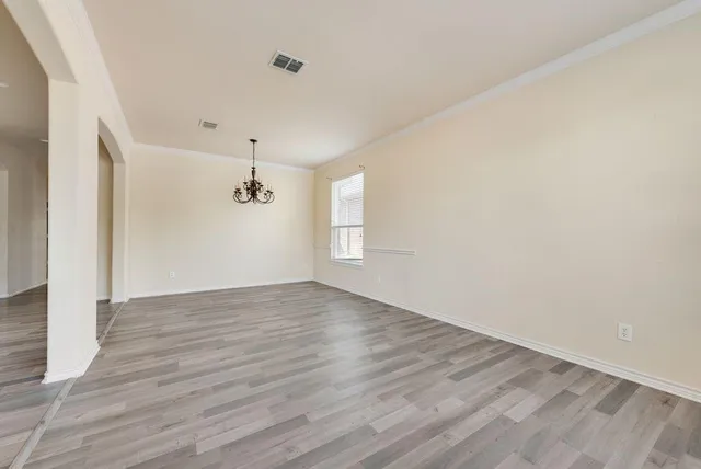 a view of an empty room with wooden floor and windows