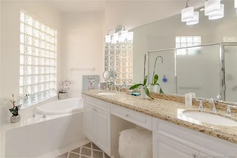 a bathroom with a granite countertop sink mirror and a bath tub