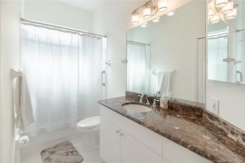 a bathroom with a granite countertop sink a toilet and shower