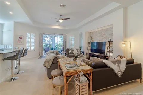a living room with furniture a ceiling fan and a flat screen tv