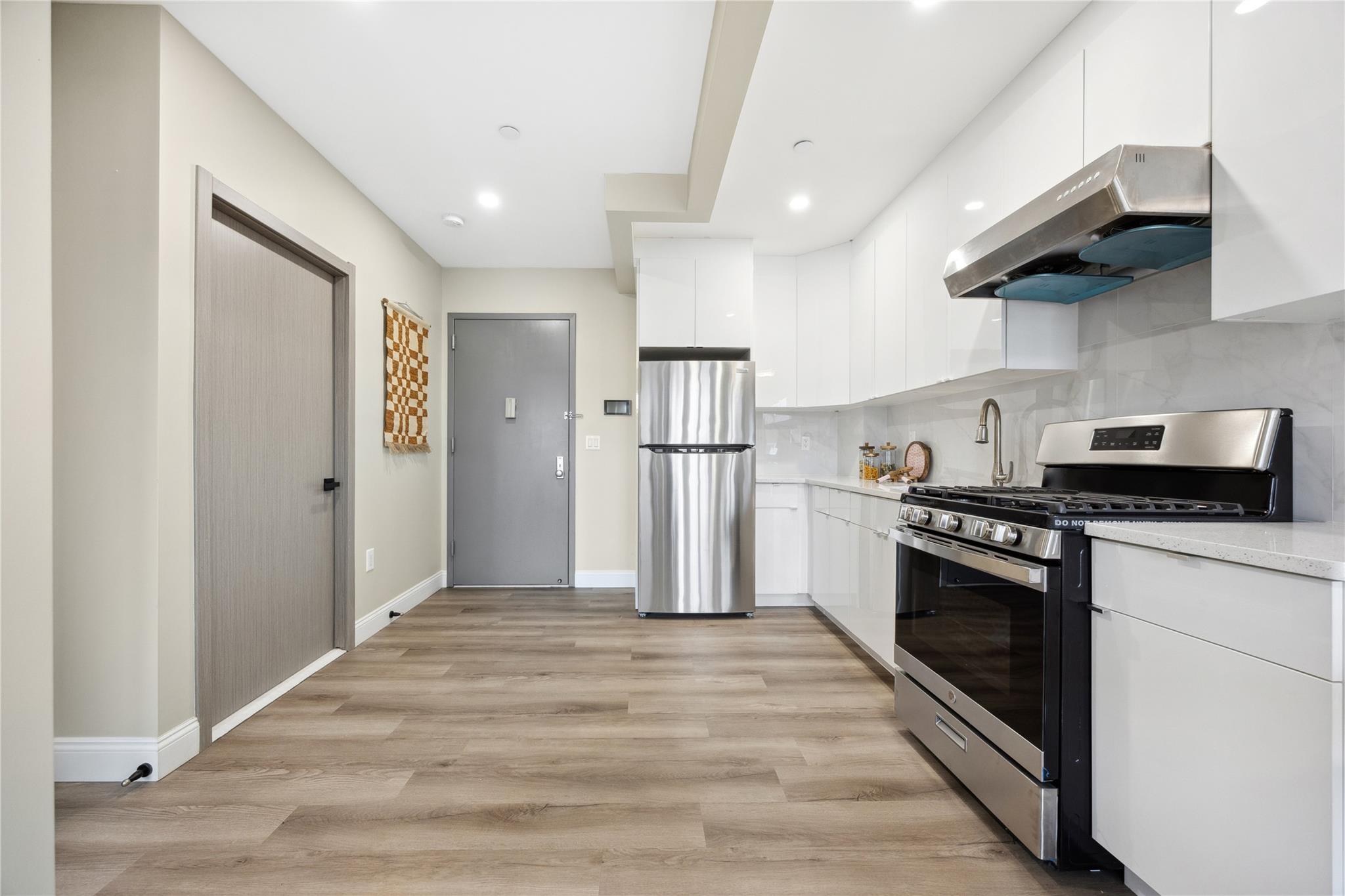 163-07 72nd Avenue, Unit 2C Queens, NY 11365 - Photo 3 of 14 Kitchen featuring range hood, stainless steel appliances, backsplash, white cabinets, and modern cabinets