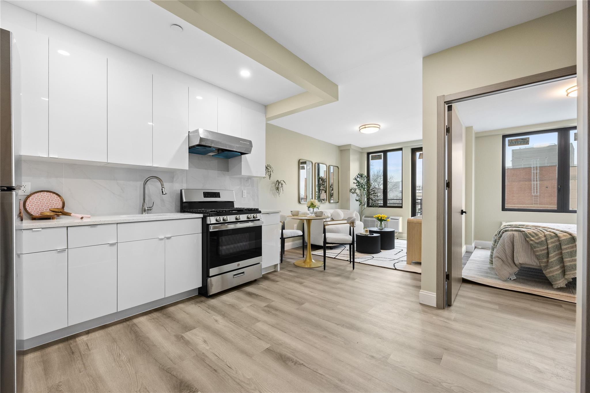 163-07 72nd Avenue, Unit 2C Queens, NY 11365 - Photo 4 of 14 Kitchen featuring light wood-style floors, light countertops, range hood, modern cabinets, and stainless steel range with gas stovetop