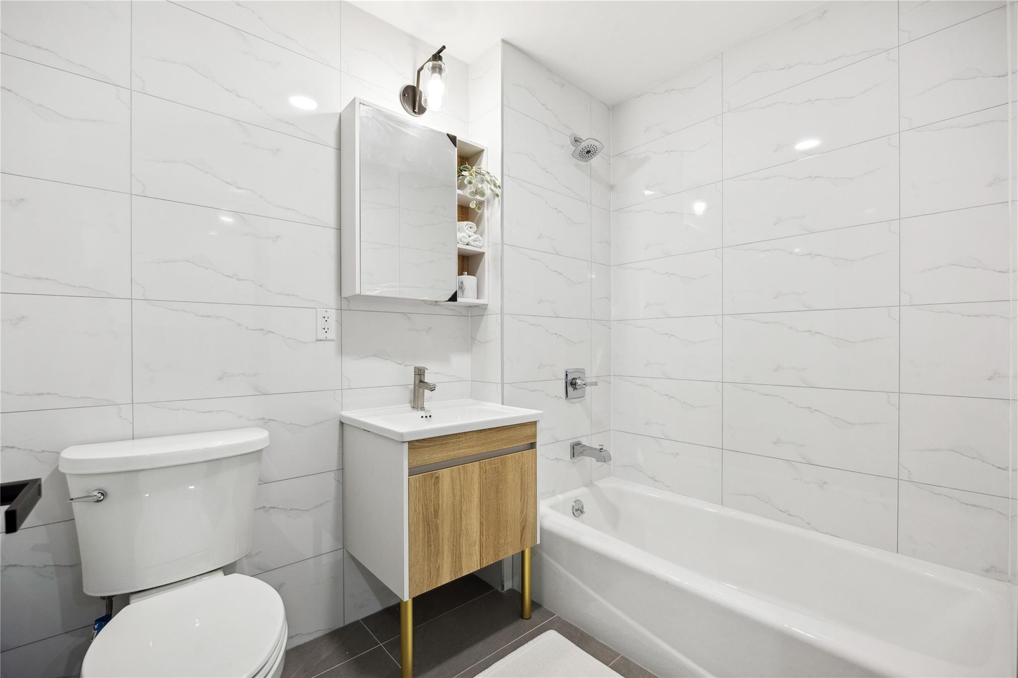 163-07 72nd Avenue, Unit 2C Queens, NY 11365 - Photo 8 of 14 Full bath with shower combination, tile walls, vanity, and toilet