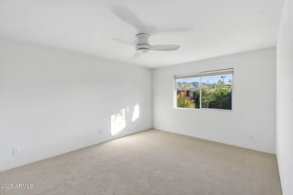 an empty room with ceiling fan and windows