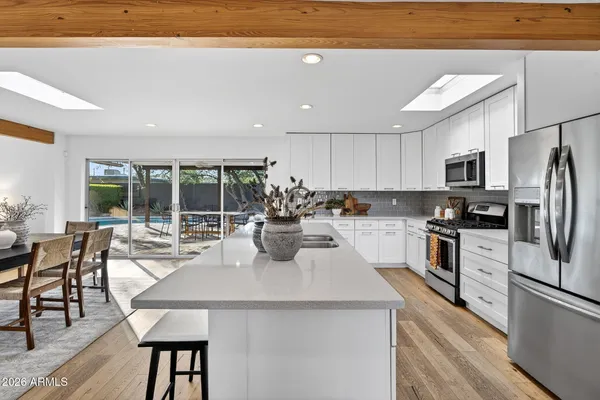 a kitchen with stainless steel appliances granite countertop a stove a refrigerator a sink dishwasher a dining table and chairs with wooden floor