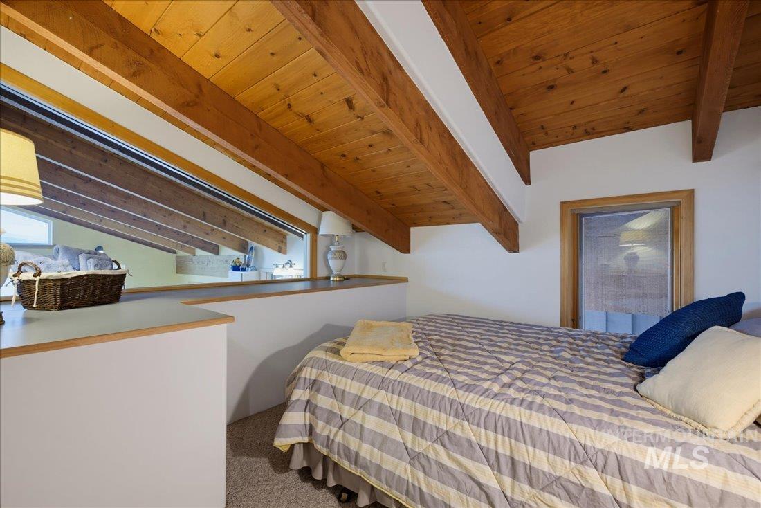 3800 Warren Wagon Road McCall, ID 83638 - Photo 25 of 50 Vaulted wood-plank ceiling with exposed beams, white painted walls, wood-trimmed window, and a built-in shelf