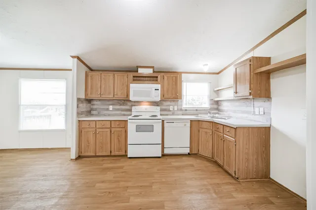 a kitchen with granite countertop white cabinets white stainless steel appliances with a sink and window