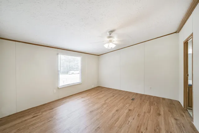 an empty room with wooden floor and windows