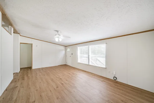 an empty room with wooden floor and windows