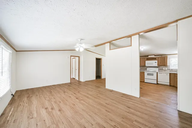 a view of an empty room with window and wooden floor