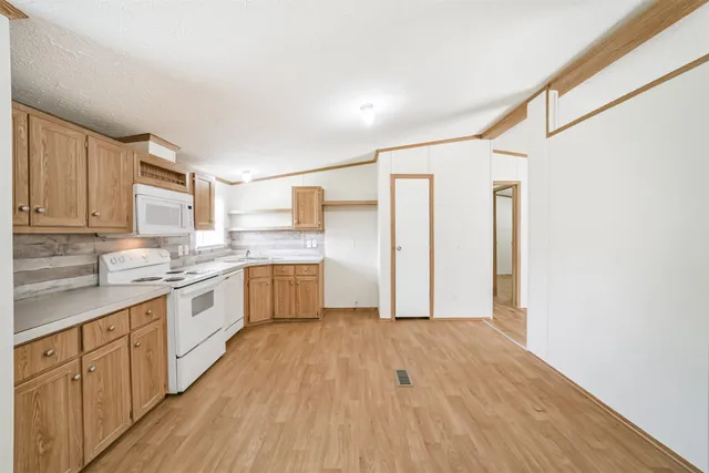 a large kitchen with a wooden floor and white stainless steel appliances