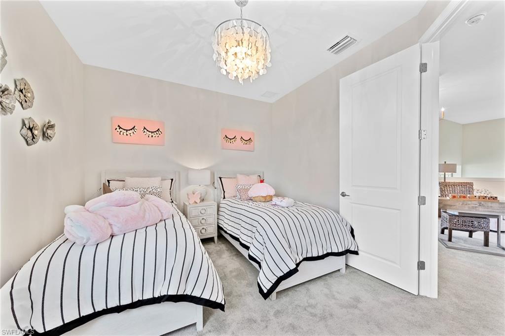 14351 Lagoon Lane Babcock Ranch, FL 33982 - Photo 31 of 39 a bedroom with two beds and a chandelier